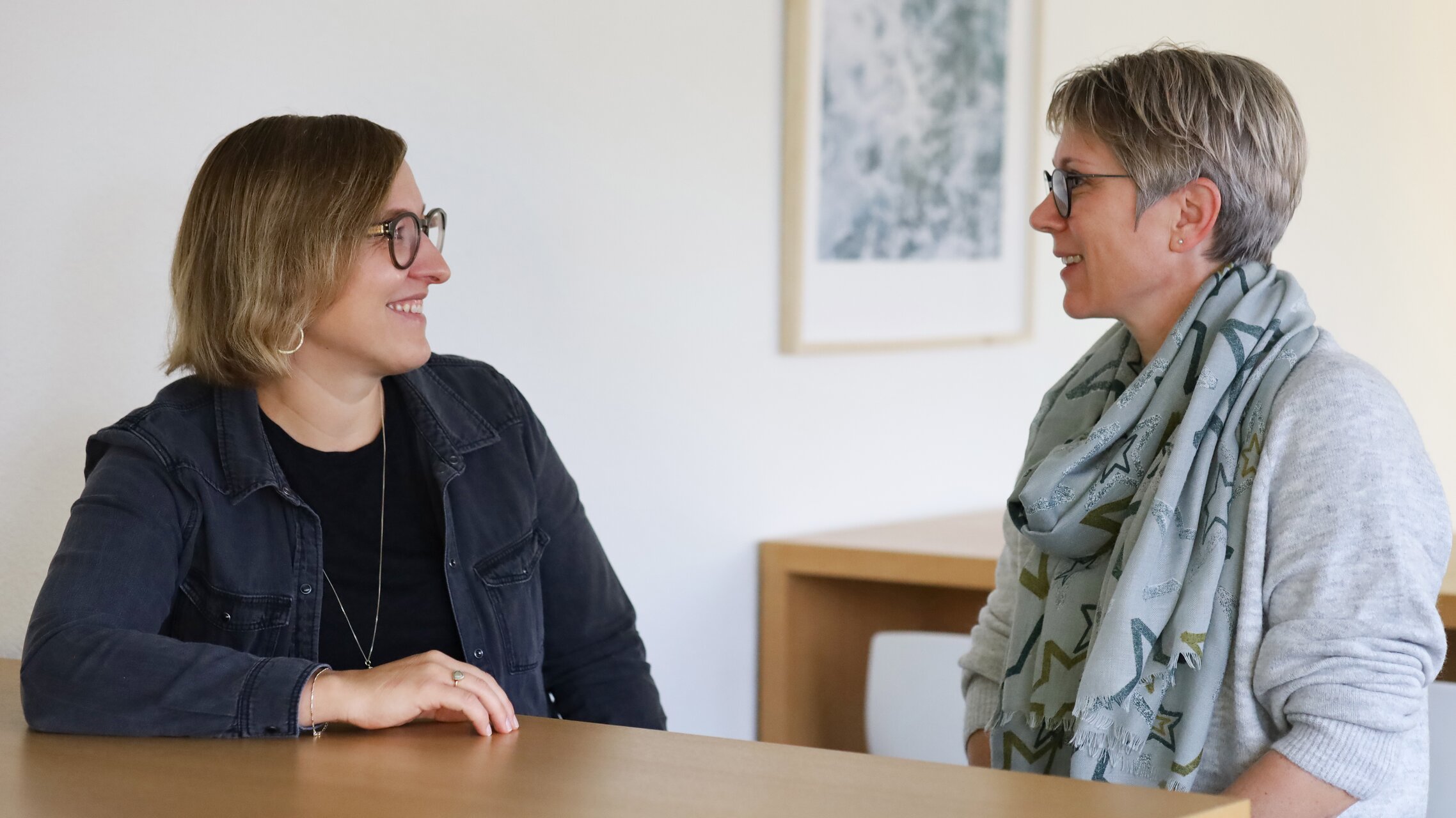 Snežana Milojević und Regula Scherer sitzen an einem Tisch in einem Büro und schauen sich an. | © ask! - Beratungsdienste für Ausbildung und Beruf