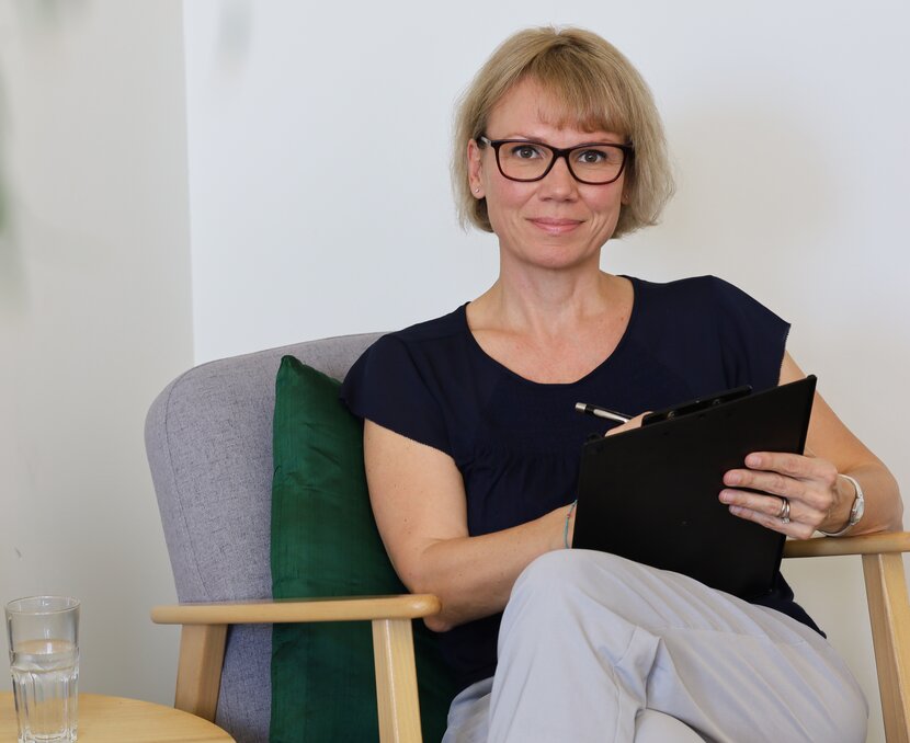 Sandra Senti sitzt auf einer Couch mit einem Klemmbrett in der Hand | © ask!