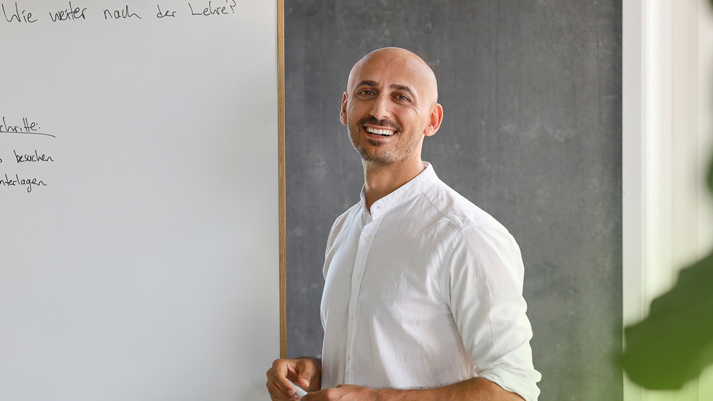 Özkan Ünlü vor einem Whiteboard mit einem Stift in der Hand in einer Beratung | © ask! – Beratungsdienste für Ausbildung und Beruf