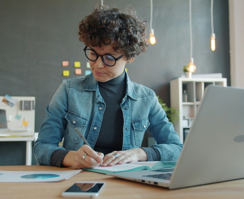 Frau vor Laptop, rechnet etwas aus, studiert Diagramm | © Unsplash, Vitaly Gariev