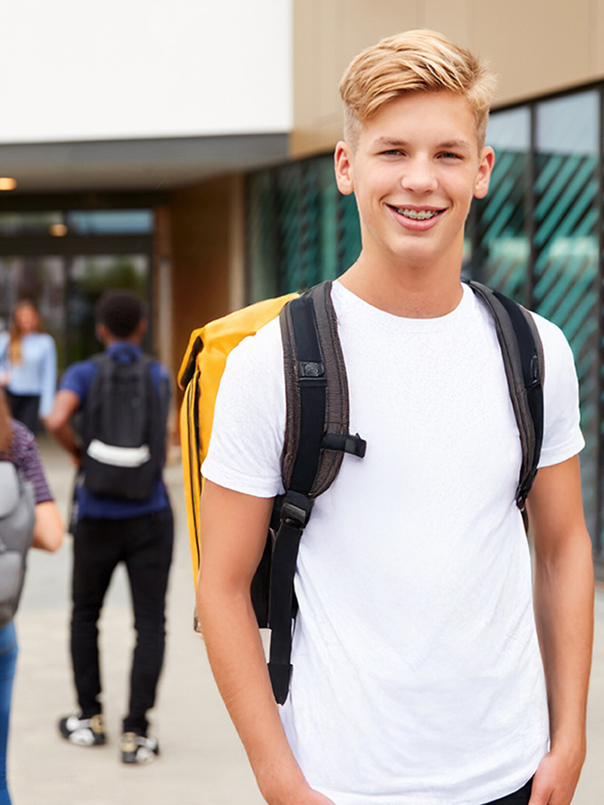 Schüler steht auf dem Schulhof und lacht in die Kamera